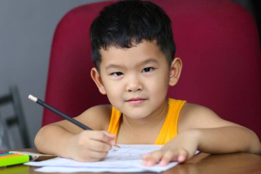 Asyalı çocuk ev ödevini yapıyor, evde yaşam konsepti, Taylandlı çocuk kendi başına öğreniyor..