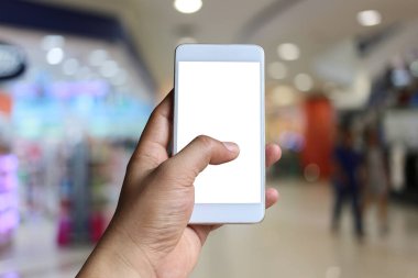 Bulanık Alışveriş merkezi arka planda akıllı telefon cihazı tutan bir adamın eli ve ekranda beyaz kopya alanı var.