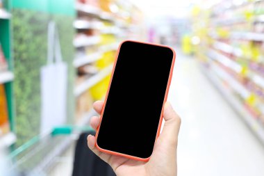 El akıllı telefonu tutuyor ve alışveriş merkezinde boş siyah bir ekranı var..