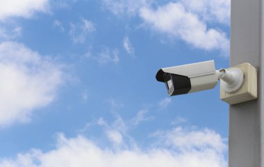 Mavi gökyüzü arkaplanı üzerindeki CCTV aracı, güvenlik sistemleri için ekipman ve tasarım için kopyalama alanına sahip.