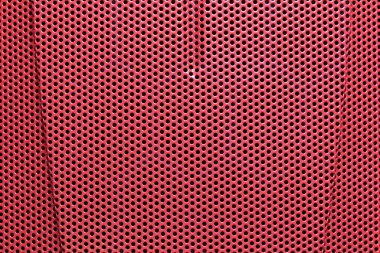 Çeşitli endüstrilerdeki modern tasarım, tekstil ve yaratıcı projeler için ideal olan üniforma deliklerinden oluşan kırmızı delikli bir maddenin yakın çekim görüntüsü..