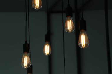 Bu büyüleyici görüntü zarif asılı ampulleri sergiliyor. Sıcak bir parıltı yayıyor, modern bir iç mekanın atmosferini güzelleştiriyor..