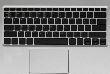 Modern bir dizüstü bilgisayar klavyesinin yakın plan görüntüsü, çağdaş bir çalışma alanında teknoloji ve iş teması için mükemmel, parlak siyah ve gümüş bir tasarım sergiliyor..