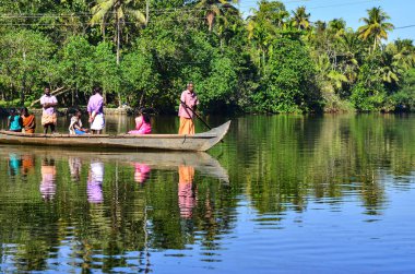 Alleppey, Kerala, Hindistan, 2019. Yaşlı adam kürek teknesi göl kapısı yerel yolcu taşıyan. Hindistan cevizi ağaçlarının arka plan ve Alappuzha, Alleppey, Kerala, Hindistan arka mavi sularına karşı atış