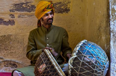 Jodhpur, Rajasthan, Hindistan, 2020. Geleneksel Rajasthani davulcusu Mehrangarh Kalesinde sarı pagdi takmış davul çalıyor..