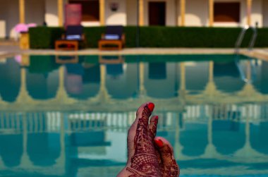 Yeni evli kadın bir yüzme havuzu bir tatil beldesine Jaisalmer, Hindistan onun balayına önünde kına ayaklı