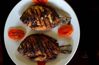 Üstten görünüm kızarmış balık yemeğin Kerala. 2 balıklar kızarmış ve beyaz seramik tabakta domates ile süslenmiş ızgara