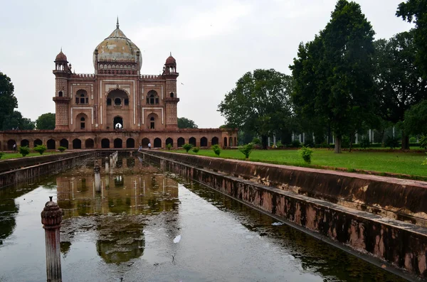 Safdarjung Tomb against the blue sky looking majestic between palm trees. Shot on a day with blue sky & beautiful warm sunlight. Reflection at the fountains & gardens make this a great tourist spot