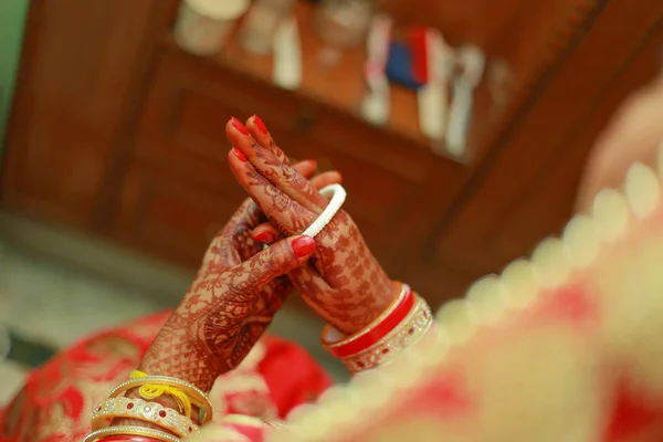 Indian Bengali bride wearing wedding traditional red bangles (choora) and getting ready for her wedding ceremony in Delhi, India