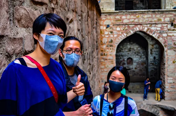 3 Asian tourists wearing masks visiting Ugrasen ki Baoli, a heritage monument in Delhi, India, Circa 2018. Delhi has become an extremely polluted city and it\'s difficult to breathe even for the locals
