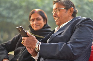 Delhi, Hindistan bir parkta mobil ve konuşan, gülümseyen üzerinde çalışan üst düzey çift