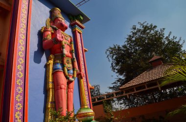 Yan düşük açı görünümü eski büyük kırmızı renkli Hindu tanrısı Hanuman heykeli Delhi'de bir Tapınak binası dışında, Hindistan