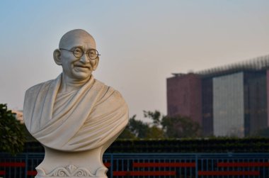 Bust of Gandhi statue with LIC building in the background in the Charkha Museum in Connaught Place. Mahatma Gandhi is the Father of the Nation. clipart