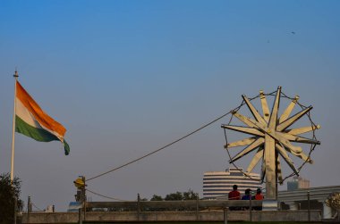 Giant spinning wheel against the backdrop of waving Indian tricolor in Ahmadabad, Surat, Gandhinagar, Gujarat, Delhi, India. Charkha (Spinning wheel) was made popular by Mahatma Gandhi when he used it to spin his own khadi clothes. clipart
