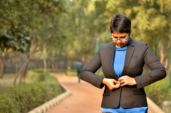 Young Indian woman working business professional looking down while buttoning her jacket back in a formal corporate business suit in an outdoor location