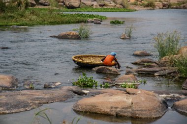 Balıkçı Tungabhadra nehri, Hampi, Karnataka, Hindistan yeni pasengers için dongi olarak bilinen onun coracle tekne hazırlanıyor