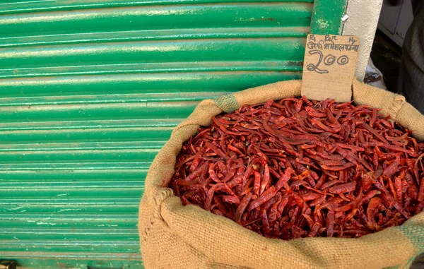Front view of dried red chilly kept in a gunny sack outside a shop in a spice market kept against green background in India, Delhi, Turkey Istanbul (translation - red chilly special price 200)