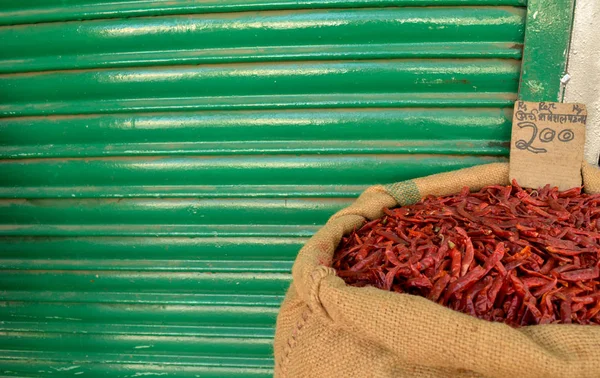 Dried red chilly kept in a gunny sack outside a shop against green background in spice market India, Delhi, Turkey Istanbul (translation - red chilly special price 200)