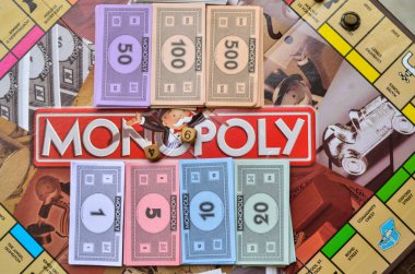 fake money neatly arranged on monopoly board game