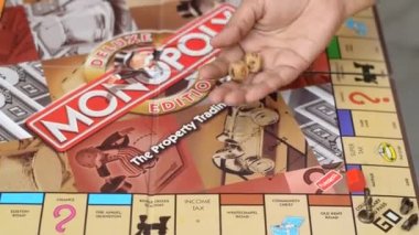 London, England, UK, 2020. Player Rolling dice on a Monopoly board. Monopoly has become a part of popular world culture, it's locally licensed used as a fun financial educational game worldwide