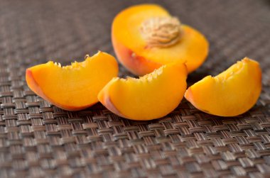 Şeftali yarım ve daha küçük dilimler halinde bir masa mat süslenmiş kesilmiş