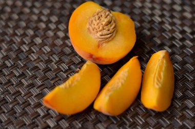 Şeftali yarım ve daha küçük dilimler halinde bir masa mat süslenmiş kesilmiş