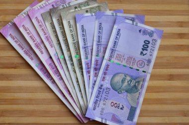 Ahşap arka plana karşı demonetization sonra yayınlanan ve dolaşımda 100, 500 ve 2000 rupi demet yepyeni renkli Hint para banknotlarının Closeup
