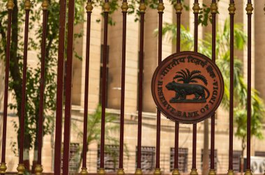 RBI logo on the closed iron gate of Reserve Bank of India (RBI) building at Patel Chowk, Connaught Place with the office building in the background in Delhi, India clipart