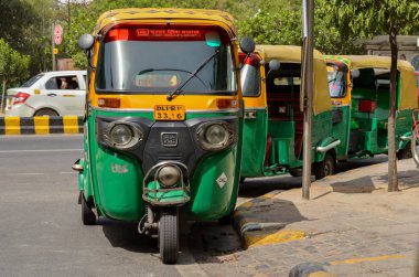 Emphatic looking CNG fueled autorickshaw, standing on the corner of the road in Delhi, India. It is a popular urban transport on Indian roads in Mumbai, Pune, Lucknow, Jaipur, Hyderabad, Bangalore clipart