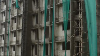 Yoğun bir caddenin kenarındaki inşaat binalarının altında. İnşaat vinçleri, güvenlik ağları ve çitler burayı düzgün bir inşaat alanı yapıyor. Dünyanın dört bir yanında böyle binalar görülebiliyor.