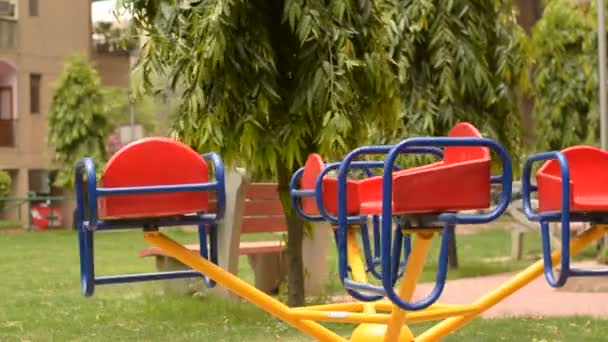 一个空的旋转木马在公园里旋转 背景是树木和草 空座位表示孩子们更喜欢使用技术 而不是在春天在公园里玩耍 — 图库视频影像
