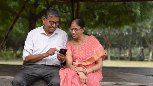 Пожилая Индийская Пара Читает Мобильного Телефона Улыбается Парке Летом Дели — стоковое видео
