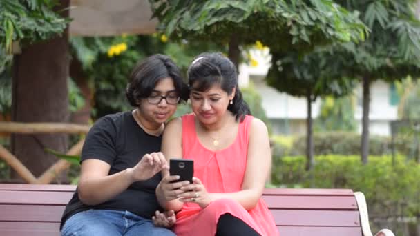 Deux Amis Assis Sur Banc Parc Rouge Regardant Dans Téléphone — Video