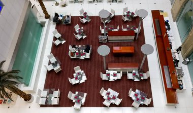 Dubai, Uae. Atrium manzaralı büyük bir salonda güzel bir masa ve bir kafe ve açık büfede sandalyeler var..