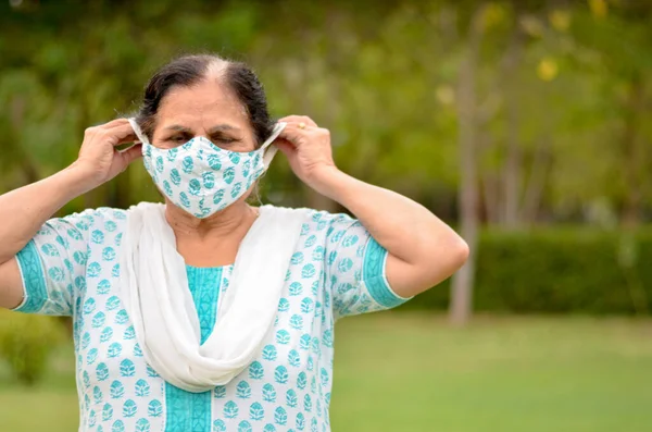 Close up Portrait of a senior Indian lady and young lady wearing surgical cotton mask matching with her salwar kameez to protect herself from Corona Virus (COVID-19) pandemic, getting ready in India