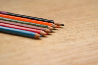 Keskinleştirilmiş renkli kalemlerle ahşap bir tahtaya yerleştirilmiş soyut Düz Yatır / Düzen. Burada mavi, kırmızı, turuncu, yeşil, siyah renkler görülür.