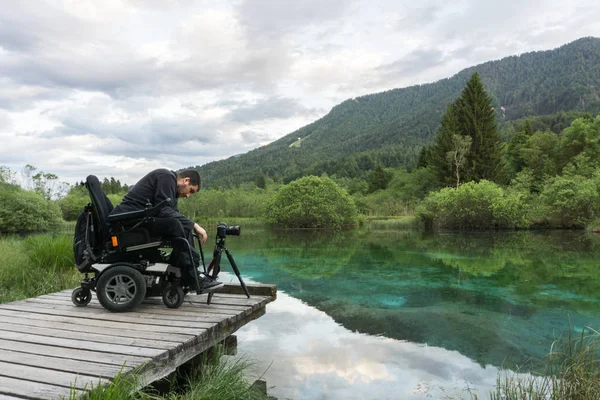 自然の湖の近くのミラーレス カメラを用いた車椅子の男 — ストック写真
