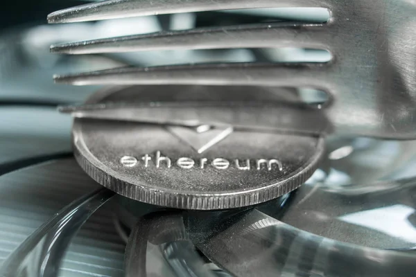 Ethereum cryptocurreny moneda colocada en la tarjeta gráfica de la GPU y tenedor tratando de la mitad, tenedor duro — Foto de Stock