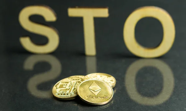 Security Token Offering STO sign with wooden letters and gold coins in front of it, Ethereum concept
