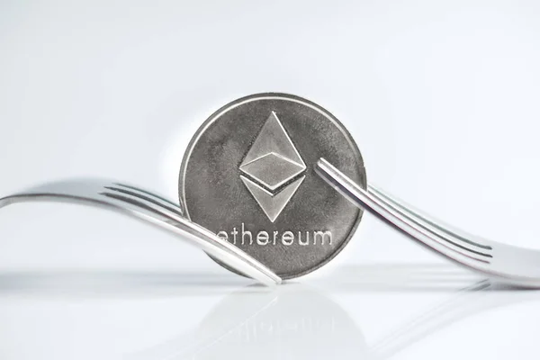 Moneda de criptocurrenia Ethereum colocada entre horquillas con reflejo, horquilla dura sobre fondo blanco — Foto de Stock