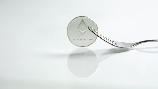 Zoom deslizante em tiro do conceito garfo Ethereum com moeda Ethereum e um garfo no fundo branco com reflexão — Vídeo de Stock