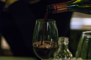 Garson bardağa kırmızı şarap dolduruyor..