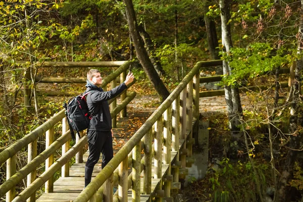 Viajero tomando selfie con smartphone en puente de madera en el bosque —  Fotos de Stock