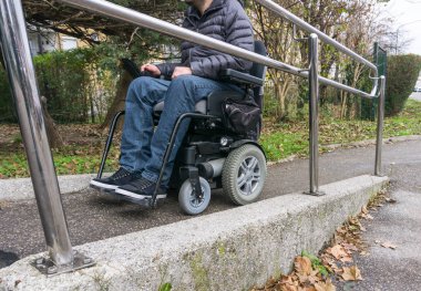 Adam bir rampa yanındaki merdivenleri kullanarak tekerlekli sandalyede
