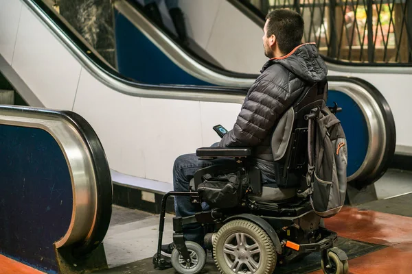 Vista trasera de un hombre discapacitado en silla de ruedas delante de escaleras mecánicas — Foto de Stock