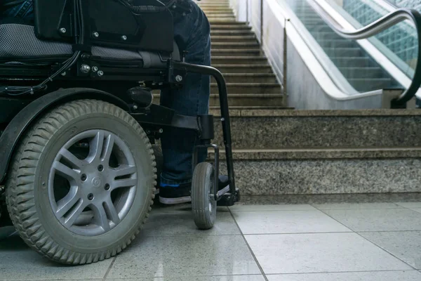 Foto de primer plano del hombre en una silla de ruedas delante de escaleras mecánicas y escalera con espacio para copiar — Foto de Stock