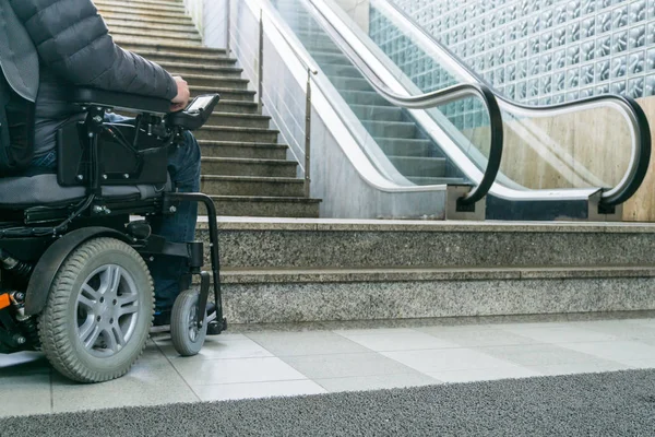 Foto de primer plano del hombre en una silla de ruedas delante de escaleras mecánicas y escalera con espacio para copiar — Foto de Stock