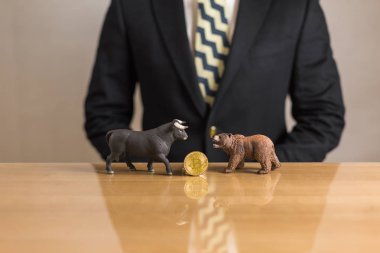 Genç işadamı tüccar ayı ve boğa figürleri ve bitcoin bakarak. Boğa ve Bearish Pazar kavramı.