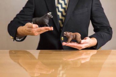 Ayı ve boğa resimler elinde tutan genç işadamı tüccar. Boğa ve Bearish Pazar kavramı.
