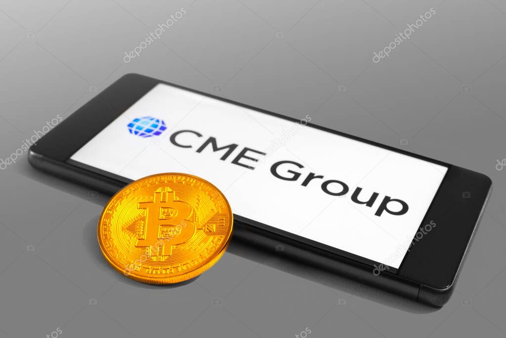 SLOVENIA - DECEMBER 16, 2018: CME Group logo on a mobile device with Bitcoin coin